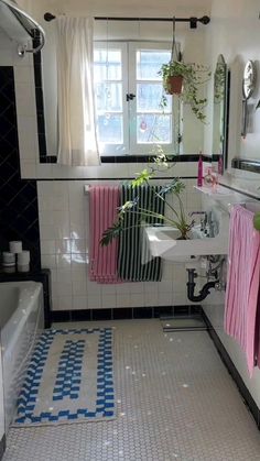 a bathroom with black and white tile, pink towels hanging on the wall, and blue and white floor tiles