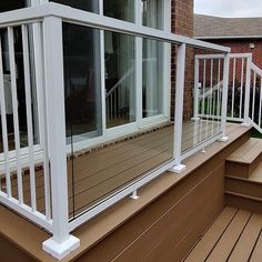 a deck with white railing and glass windows