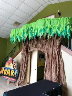 a fake tree with green leaves on it and a sign that says roar in front of it