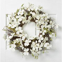 a wreath with white flowers hanging on a door