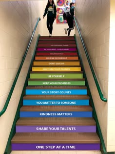 two girls are walking down the stairs with their backs to each other and there is an advertisement above them