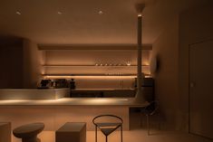 a dimly lit kitchen with bar stools and countertop space in the center,