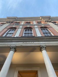 an old building with columns and windows on the front side, against a blue sky