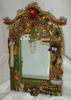 a mirror with many different things on it and gold trim around the edges, hanging from a white wall