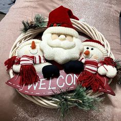 a christmas wreath with santa claus and snowmen on it, sitting in front of a welcome sign