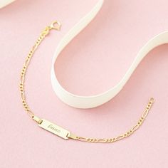 A classic engravable tag id bracelet for baby girls and boys that features an elegant figaro chain. This bracelet is crafted from genuine 14k yellow gold, a material that is safe for your baby with sensitive skin. This classic bracelet makes for a beautiful gift for a baby or toddlers special birthday. Gift box included with purchase. Personalized Yellow Gold Rectangular Name Bracelet, Personalized Rectangular Yellow Gold Name Bracelet, Elegant Hypoallergenic Nameplate Bracelet, Classic Yellow Gold Nameplate Bracelet, Classic Rectangular Name Bracelet, Tarnish Resistant, Classic Adjustable Gold Bracelet With Name, Classic Adjustable Gold Bracelet With Name Detail, Classic Tarnish Resistant Name Bracelet, Yellow Gold Nameplate Bracelet With Engraving Option