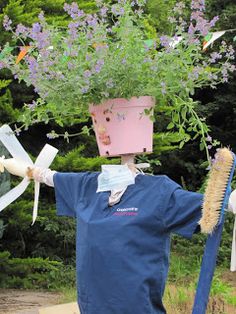 a scarecrow holding a potted plant on top of his head