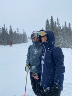 two people standing in the snow with skis on