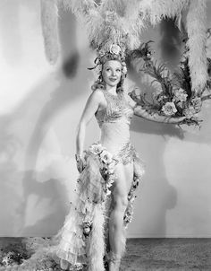 an old photo of a woman in a costume with feathers and flowers on her head