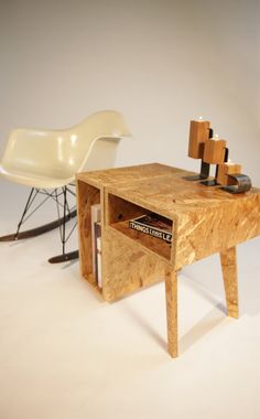 a wooden table with a magazine rack on it next to a white chair