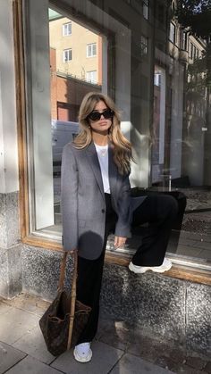 a woman is sitting on a window sill with her hand in her pocket and holding a purse