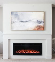 a white fireplace with a painting on the wall above it and a fire place in front of it