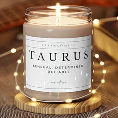 a candle that is sitting on top of a wooden table with lights around it and the words taurus