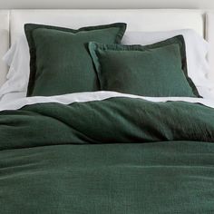 a bed with green sheets and pillows on it