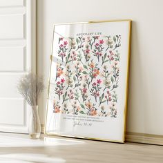 an open book sitting on top of a wooden floor next to a vase with flowers