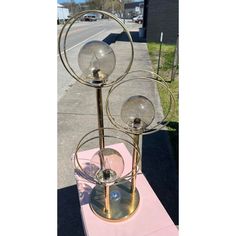 a metal stand with three glass balls on it and a pink table cloth under it