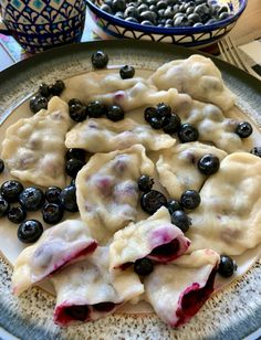 blueberries and cream cheese ravioli on a plate next to bowls of olives