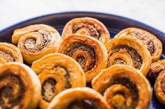 there are many cinnamon buns in the blue bowl on the table, ready to be eaten