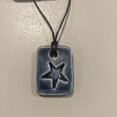 a blue and white square with a star on it is hanging from a black cord