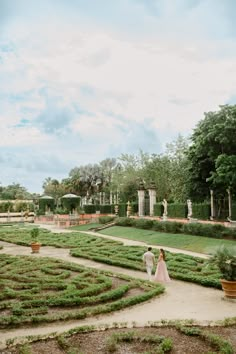 a bride and groom walking through a garden