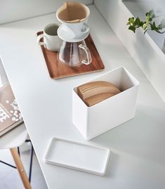 a wooden cutting board sitting on top of a table next to a cup and saucer