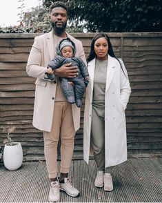 a man and woman standing next to each other with a baby in their lap,