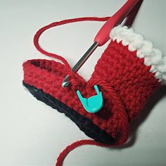 a pair of red crocheted slippers being worked on by a sewing machine