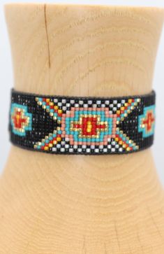 Introducing our southwestern cross cuff bracelet- perfect for adding a touch of boho chic to any outfit! This bracelet is handmade with black leather trim and colorful seed beads, and features an adjustable closure for a perfect fit. It is beaded on strong beading thread & flexible natural leather for comfortable stylish look. It can be worn alone or stacked with other pieces. 7/8 of an inch wide. This bracelet will fit a 6-8 inch wrist. When you purchase this bracelet, I make it to order, just Adjustable Black Cuff Bracelet With Colorful Beads, Handmade Southwestern Black Beaded Bracelets, Southwestern Black Beaded Bracelets, Handmade Black Southwestern Beaded Bracelets, Black Beaded Southwestern Bracelets, Southwestern Style Black Beaded Bracelets, Artisan Black Beaded Bracelets With Colorful Beads, Adjustable Multicolor Southwestern Cuff Bracelet, Southwestern Black Beaded Bracelet With Colorful Beads