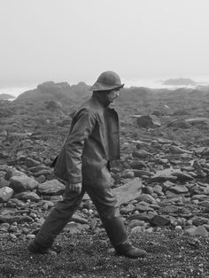 a man walking across a rocky beach next to the ocean