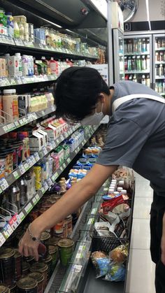 a woman picking food from a shelf in a grocery store