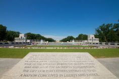 the memorial is surrounded by white pillars and green grass with blue skies in the background