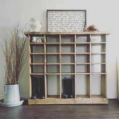 a wooden shelf with boots on it next to a potted plant