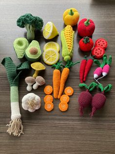 crocheted vegetables and fruits are laid out on a wooden surface, ready to be used