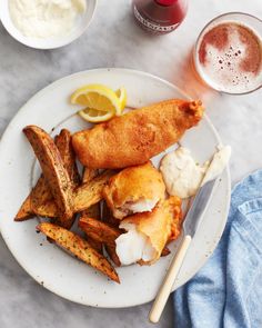 a white plate topped with fried fish and french fries next to a cup of ice cream