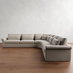 a large sectional couch sitting on top of a wooden floor next to a white wall