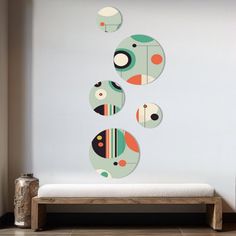 three circles are hanging on the wall above a bench in front of a white wall