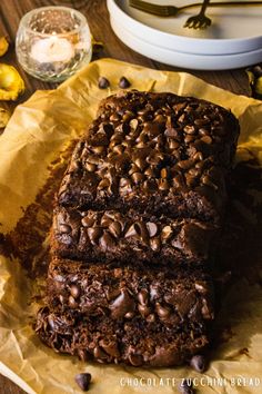 two slices of chocolate cake sitting on top of parchment paper next to a plate with lemons