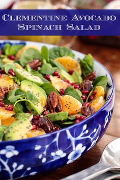 a blue bowl filled with spinach and oranges on top of a wooden table