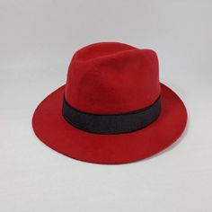 Only size:62cm. The hat's brim is asymmetrical and it also includes an additional rubber band for added style. The whole look can be seen in the attached pictures. This hat is a part of our company's archival collection. Introducing the iconic fedora hat, expertly crafted using traditional sewing techniques to ensure a flawless finish. This timeless design features a built-in lining for extra comfort and warmth, while its sleek black band and sturdy construction make it suitable for all weather conditions, making it a reliable choice for any occasion. Made from premium wool fabric, this fedora exudes sophistication with a touch of vintage charm.  WPZ-BSS-W10-62-v1259 Red Fedora With Curved Brim For Formal Occasions, Red Brimmed Fedora For Formal Occasions, Red Short Brim Fedora For Formal Occasions, Red Fitted Fedora With Curved Brim, Fitted Red Fedora With Curved Brim, Classic Red Fedora Felt Hat, Vintage Red Fedora With Curved Brim, Red Formal Fedora Felt Hat, Red Fitted Fedora For Party