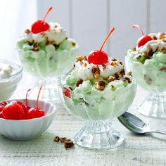 three desserts with cherries, whipped cream and pecans in glass bowls on a table