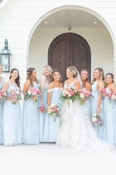 a group of bridesmaids standing in front of a church with their bouquets