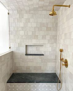 a white tiled shower with black and gold fixtures