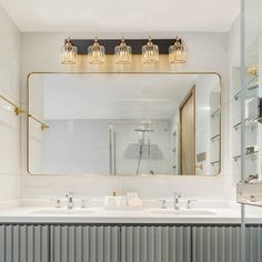 a bathroom with two sinks and a large mirror over it's head, in front of a white wall