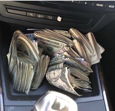 a pile of money sitting in the center console of a car