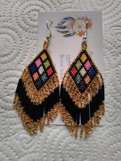 These Earrings are made by hand by me. There are 9 triangles in different colors bordered in Black and Gold. They have Gold and Iris Fringe approximately 1 1/4 inches long. They are in total 3 inches in length. They are made with Miyuki Delica size 11 seed beads. Made to Order means you purchase then I will make it within 3 days.I can make them bordered in other colors also.  Please take a close look at my work. Thank You So Very Much for your Interest Bohemian Triangle Adjustable Earrings, Bohemian Adjustable Triangle Earrings, Adjustable Bohemian Triangle Earrings, Bohemian Triangle Earrings With Ear Wire, Handmade Triangle Bohemian Jewelry, Handmade Bohemian Triangle Jewelry, Unique Handmade Triangle Earrings, Handmade Triangle Earrings For Festival, Multicolor Beaded Earrings With Latkans As Gift