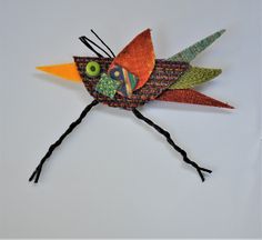 a colorful bird made out of yarn and thread on a white surface with an eye in the center