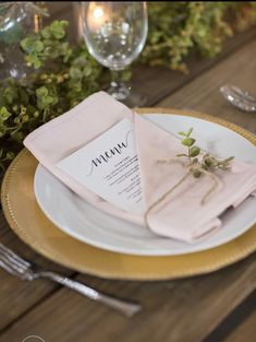 a place setting with pink napkins and greenery