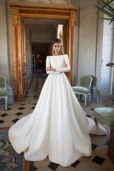 a woman in a white wedding dress posing for the camera with her hands on her hips