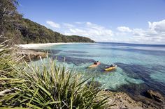 two people are kayaking in the clear blue water