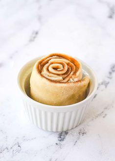 a bowl filled with cinnamon rolls on top of a marble counter